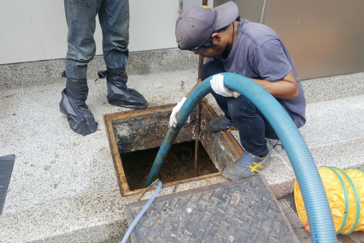 Técnico realizando a limpeza de uma caixa de gordura residencial