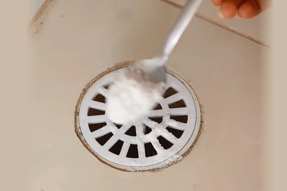 Despejando vinagre e bicarbonato no ralo do banheiro para desentupir