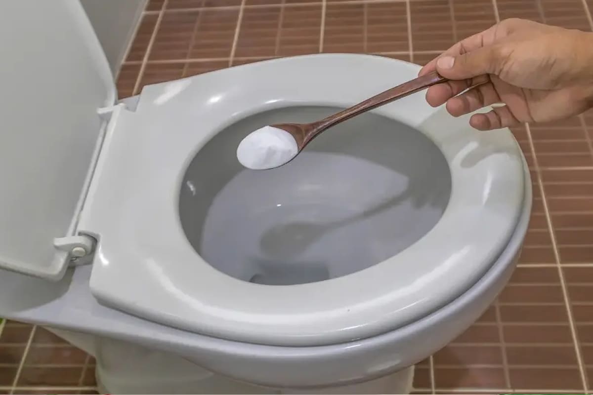 Mistura de bicarbonato e vinagre sendo aplicada no vaso sanitário