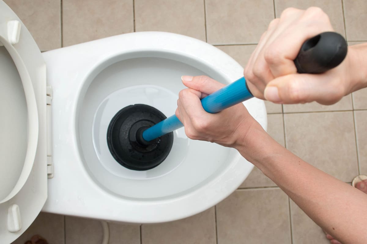 Desentupidor de borracha sendo usado em vaso sanitário entupido