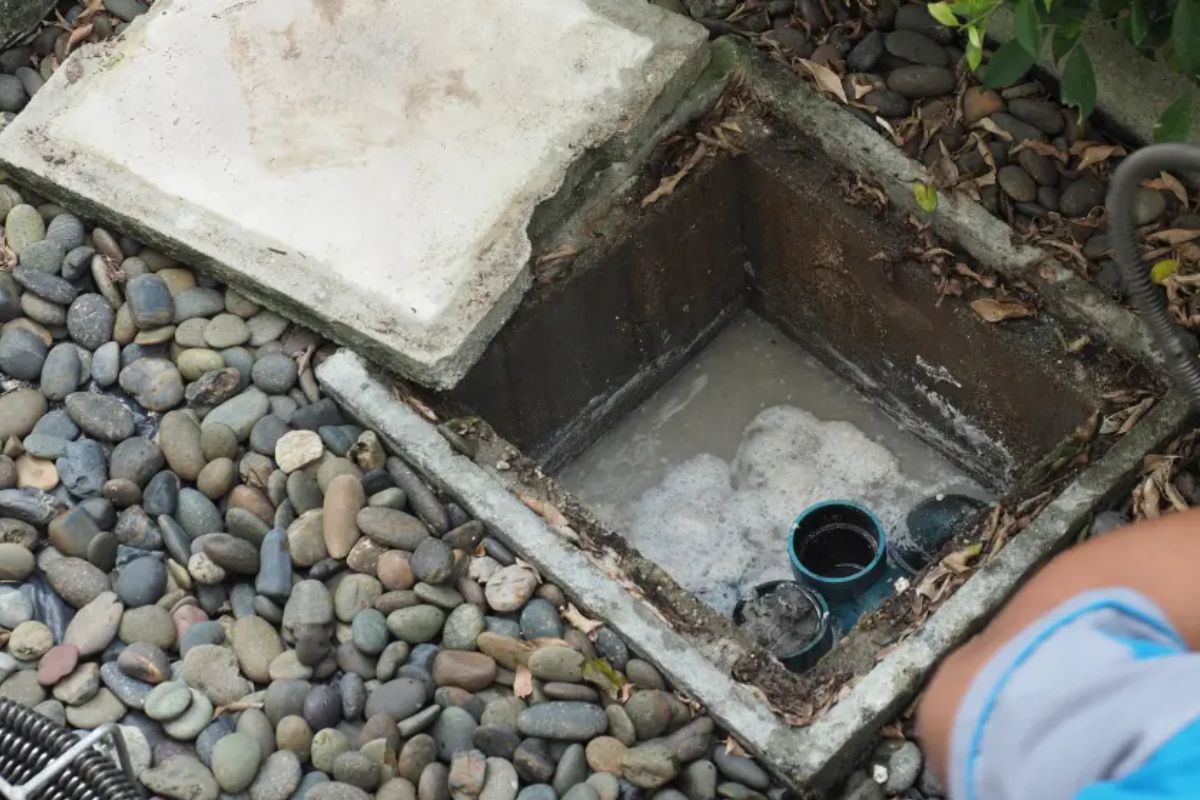 Técnico fazendo limpeza preventiva de caixa de gordura em casa