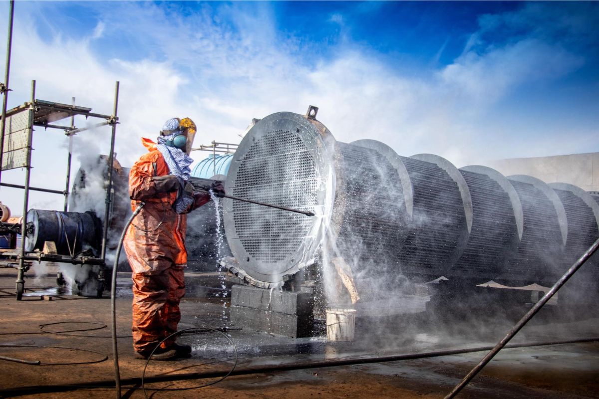Técnico utilizando equipamento de limpeza técnica em tubulação industrial